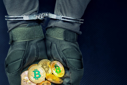 Arrested hareks handcuffs hands hold golden bitcoins.