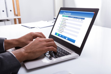 Businessperson Filling Checklist Form On Laptop