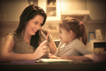 Mother teaching her little girl to draw. Close up.