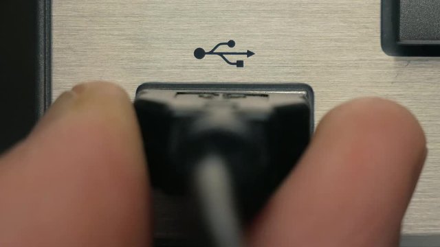 The man connects black USB cable. Close-up