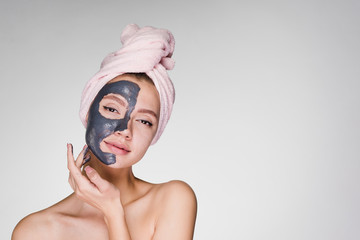 an attractive young girl with a pink towel on her head applied a useful clay mask