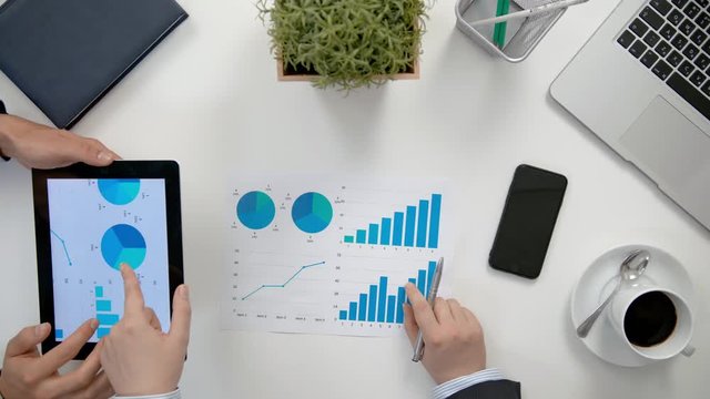 Businessmen analising diagrams in the office. View from the top of men's hands. Close-up shot.