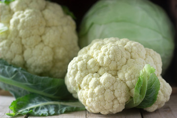 Cauliflower and cabbage on a wooden background. Rustic style, selective focus.
