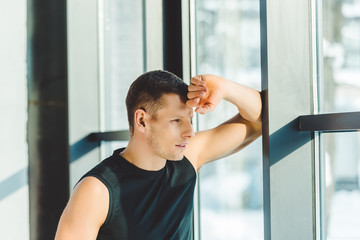 side view of pensive sportsman looking out window in gym