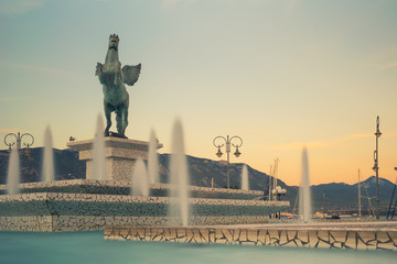 Central square of Corinth in Greece with pegasus statue against a beautiful sunset.