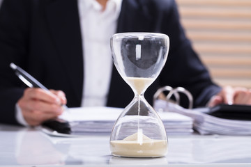Hourglass With Businesswoman Calculating Bill