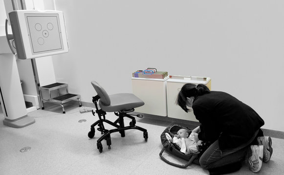 A mother with her sick infant boy about to do a X-ray examination. A black and white selective color image.