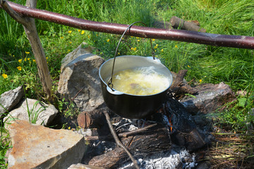 Outdoor cooking soup on the campfire. Camp cooking soup in the cauldron on the open fire.