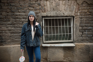 hipster girl standing near old window with lollipop 