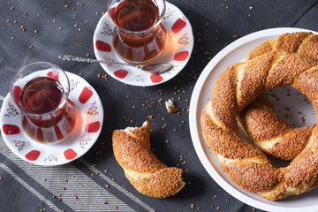 Turkish bagel Simit on the white dish with traditional tea glasses on tablecloth