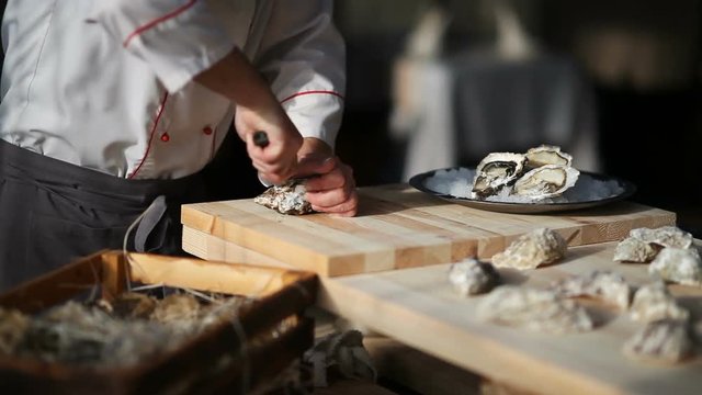 Chef trying to open fresh oyster in restaurant