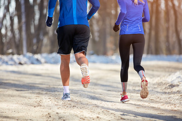 Legs of young athlete while running, back view