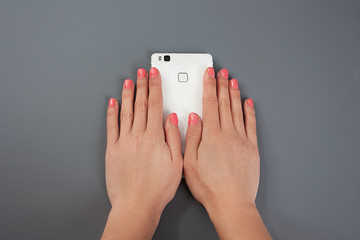 Women's beautiful, gentle hands hold a white phone. Gel-lacquer. Beautiful manicure of female hands