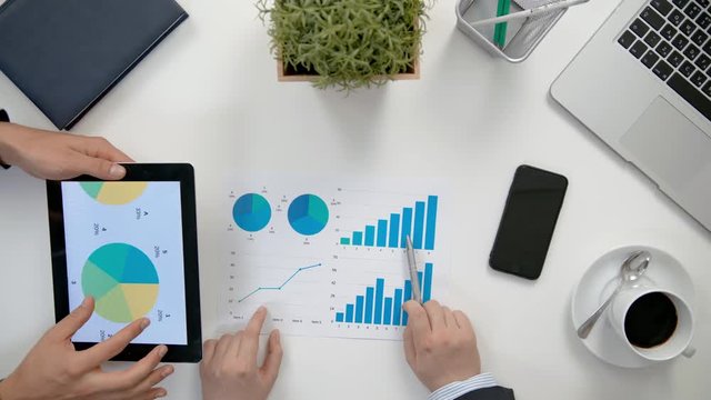 Businessmen analising diagrams in the office. View from the top of men's hands. Close-up shot.