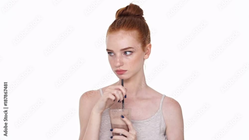 Poster displeased redhead young lady isolated over white wall background drinking hot chocolate cocoa