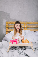 girl sitting in bed in morning with coffee and present box