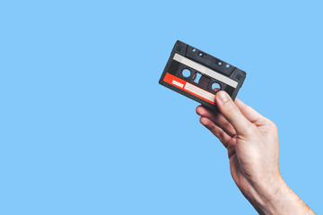 Hand holding  cassette tape. Used cassette tape. Audio cassette. Vintage audio cassette tap in the hand. Old cassette tape audio isolated on color background.