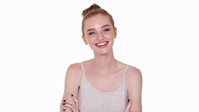 Shy cute young redhead lady looking camera isolated over white wall background while laughing
