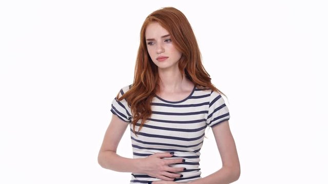 Sad redhead young lady isolated over white wall background have a painful feelings in belly