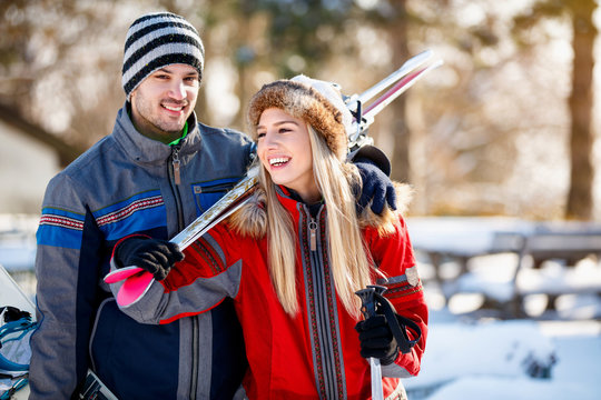 Young couple bring skis on shoulder