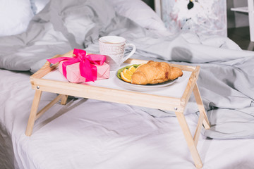 Fototapeta na wymiar tray with breakfast and present box on bed