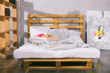 tray with breakfast and present box on bed from pallets