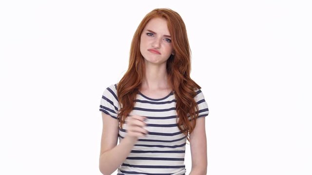 Displeased redhead young lady isolated over white wall background showing thumbs down