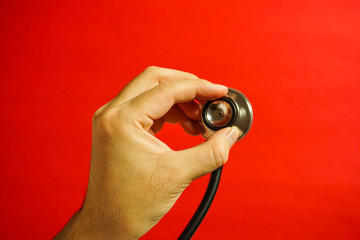 聴診器を当てる　手のみ　持ち方その２　赤色背景