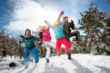 Family with children high jump on winter day on ski vacation and having fun