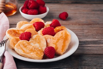 Heart shaped pancakes with raspberries and honey for St. Valentine's Day
