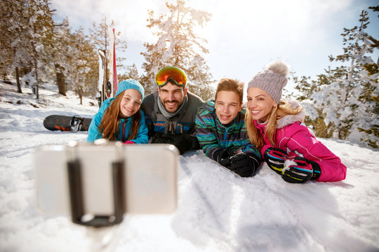 family enjoying winter vacations in mountains and making selfie