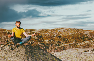 Naklejka na ściany i meble Bearded Man meditating yoga in mountains Travel Lifestyle relaxation emotional concept adventure summer vacations outdoor harmony with nature sitting on stone lotus pose