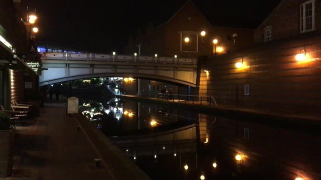 Lights reflect in the still waters of a Birmingham canal on a quiet clear night
