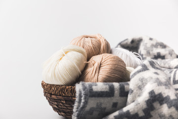 colored yarn balls in wicker basket with blanket isolated on white