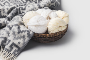 white yarn balls in wicker basket with blanket isolated on white
