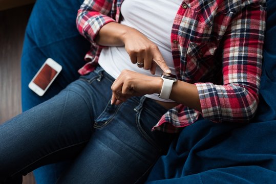 Female executive sitting on arm chair and using smartwatch