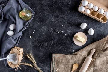flat lay with various ingredients for bread baking and cutlery on dark marble surface