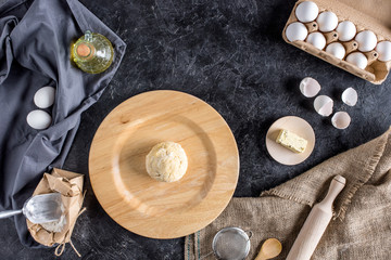 flat lay with various ingredients for bread baking and cutlery on dark marble surface
