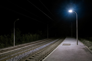 Ruhiger einsamer verlassener Bahnsteig bei Nacht mit Laternenlicht - obrazy, fototapety, plakaty