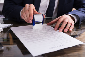 Businessperson Stamping Document In Office