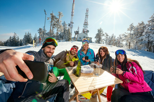group of friends laughing and enjoying in drink at ski resort