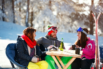 Smiling friends spending time together and drink after skiing in cafe at ski resort