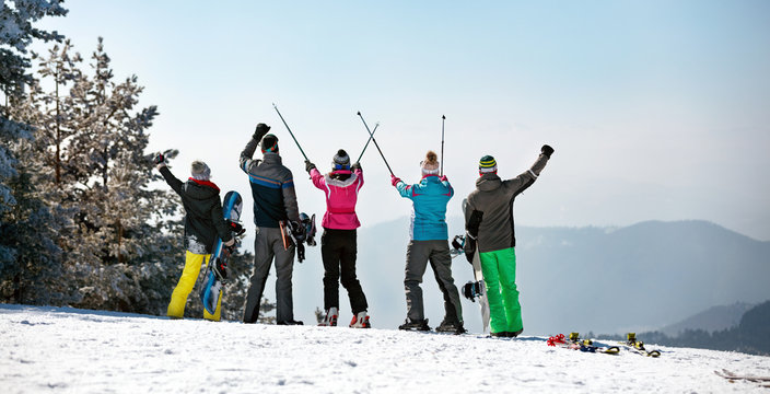 Back view of Happy skiing group on the mountain top.