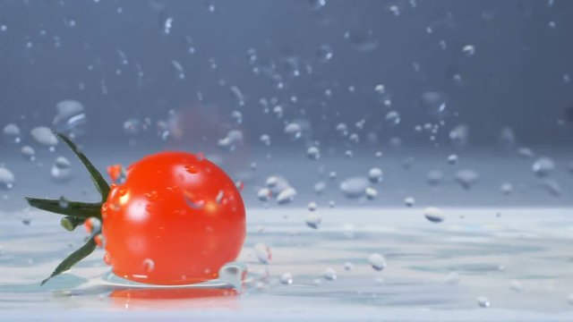 Tasty fresh tomato falls into water.