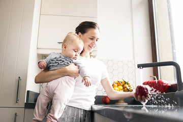 Mother with baby in kitchen. Healthy food concept