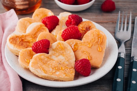 Heart shaped pancakes with raspberries and honey for St. Valentine's Day