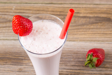 glass of strawberry smoothie with straws on a wooden table