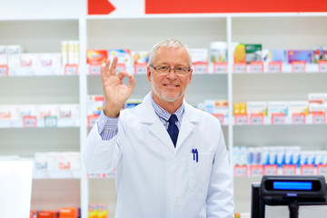 senior apothecary at pharmacy showing ok hand sign