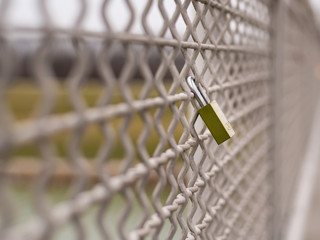 A green love padlock locked to a bridge