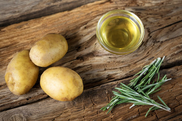 Fototapeta na wymiar potatoes with rosemary and olive oil on wooden background